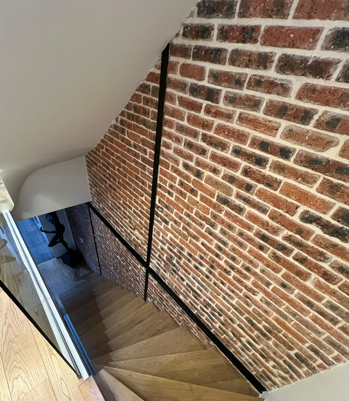 Escalier en chêne le long d'un mur en briques apparentes