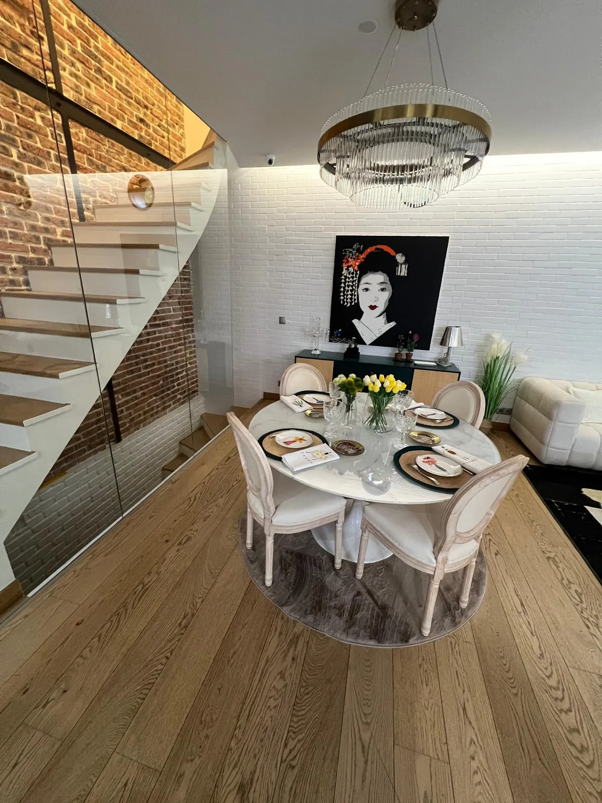 Salle à manger avec mur en briquettes blanches et escalier vitré