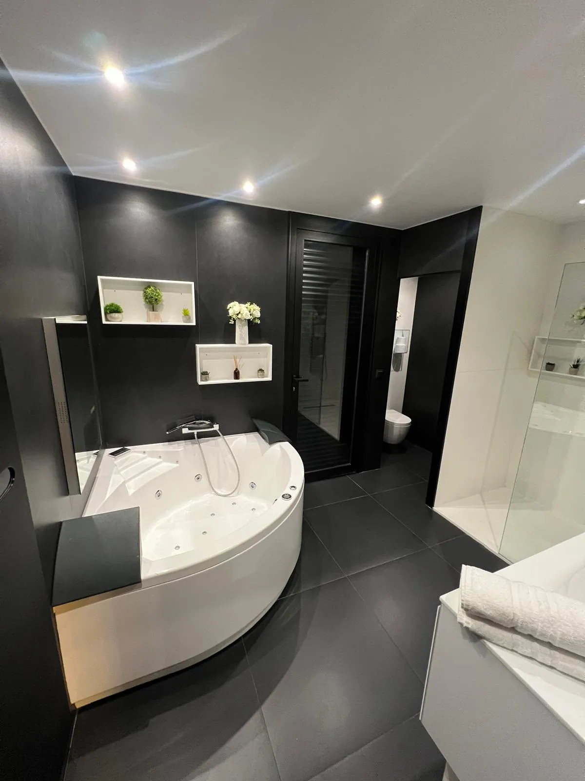 Salle de bains noire avec baignoire balnéo et douche à l'italienne réalisée par Solarius Deco