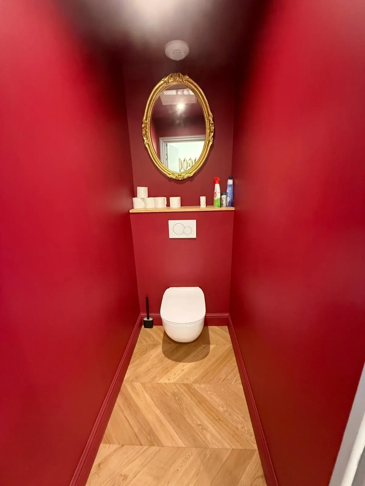 WC suspendu, murs rouges et parquet en chevrons